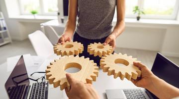 People holdiing wooden gear simpolising cooperation